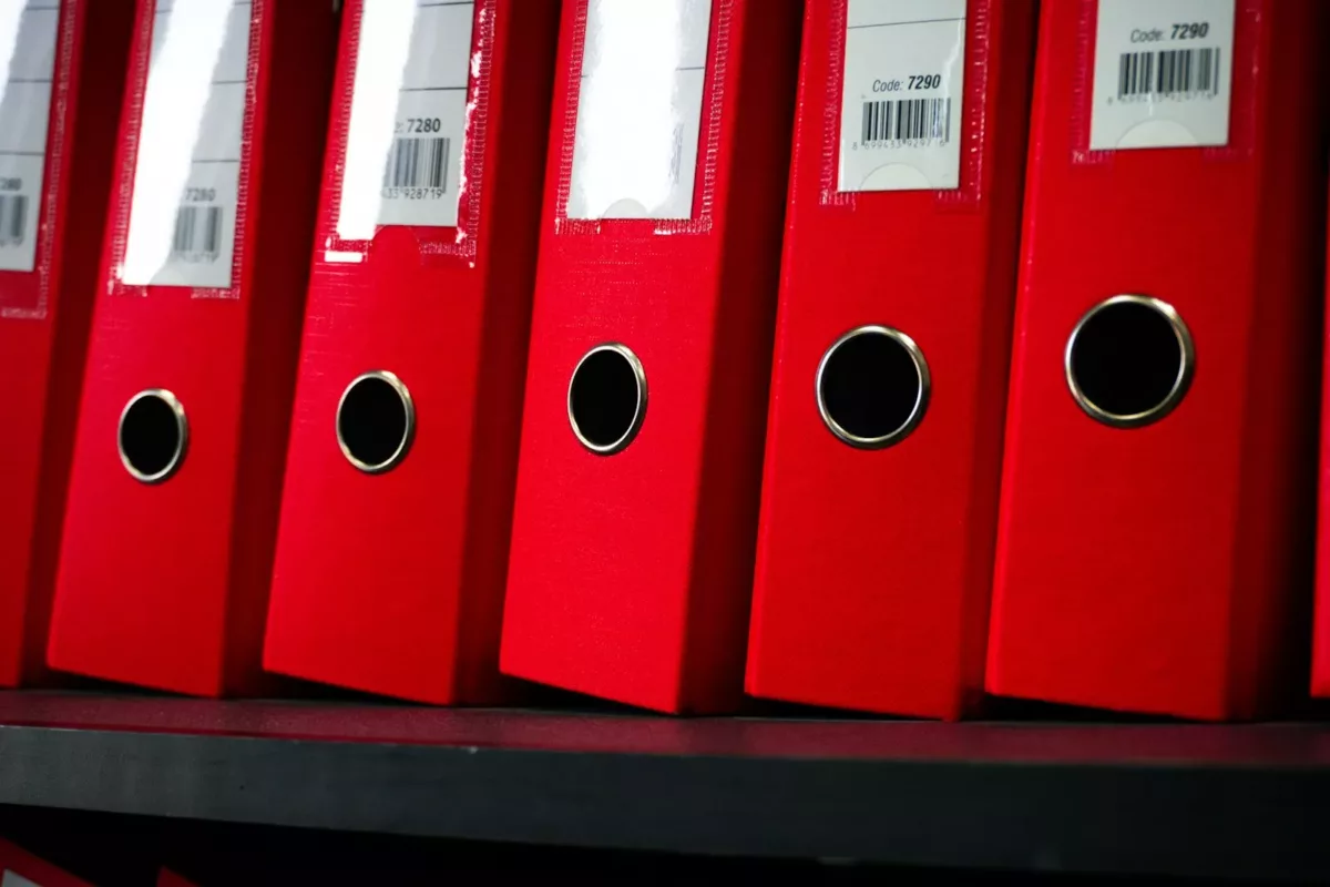 Red file folders are neatly arranged on a shelf.